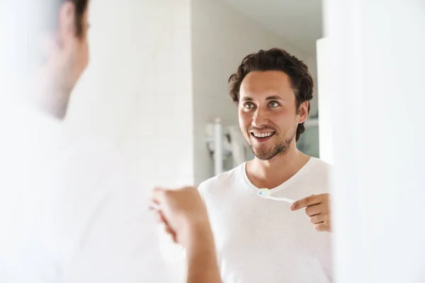 Atraktivní Šťastný Mladý Muž Stojící Před Zrcadlem Koupelně Čistící Zuby — Stock fotografie