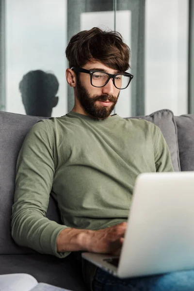 Kép Fókuszált Szakállas Férfi Szemüvegben Dolgozik Laptop Miközben Kanapén Nappaliban — Stock Fotó