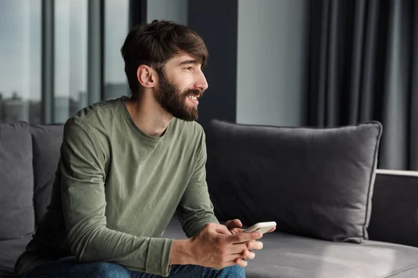 Imagen Del Hombre Guapo Alegre Sonriendo Usando Teléfono Móvil Mientras — Foto de Stock