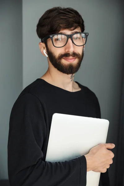 Image Young Pleased Man Holding Laptop Using Wireless Earphones While — Stock Photo, Image