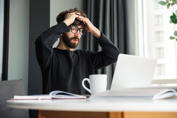 Image Young Confused Man Using Wireless Earphones Working Laptop While — Stock Photo, Image