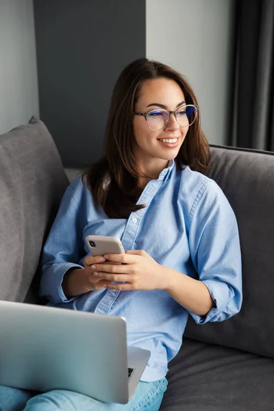 Image Happy Woman Eyeglasses Working Laptop Cellphone While Sitting Couch — Stock Photo, Image