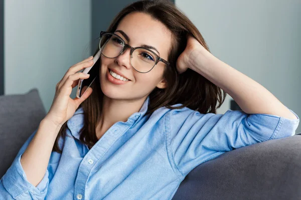 Gözlüklü Cep Telefonuyla Konuşan Oturma Odasında Otururken Gülümseyen Neşeli Bir — Stok fotoğraf