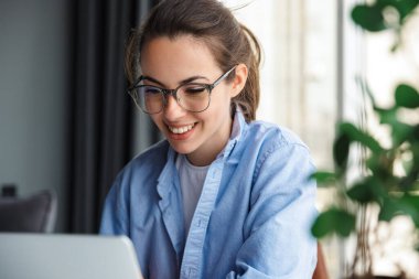 Memnun bir kadının oturma odasında otururken defter kullanıp gülümsemesi.