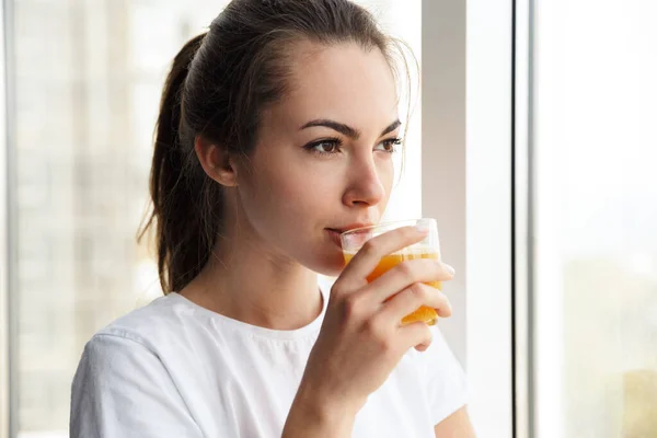 窓の外を眺めながら新鮮なジュースを飲む若い素敵な女性の焦点の画像 — ストック写真