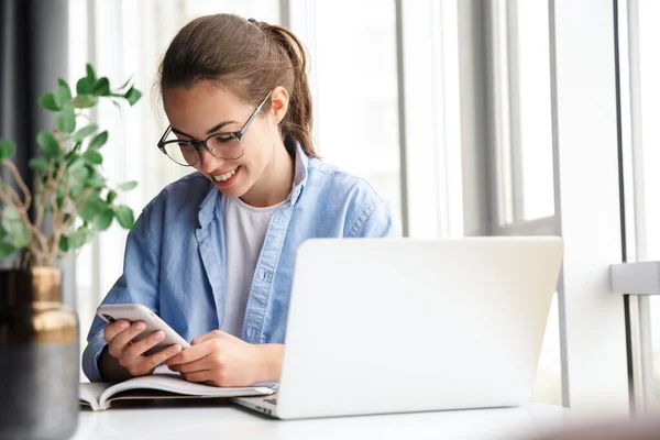 Imagem Mulher Agradável Sorrindo Trabalhando Com Laptop Celular Enquanto Sentado — Fotografia de Stock