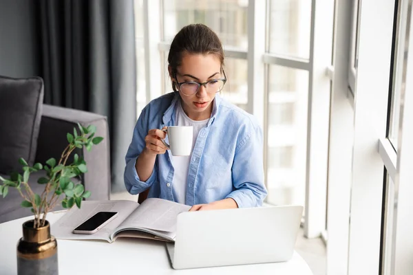 Bild Vacker Fokuserad Kvinna Dricka Och Arbeta Med Laptop När — Stockfoto