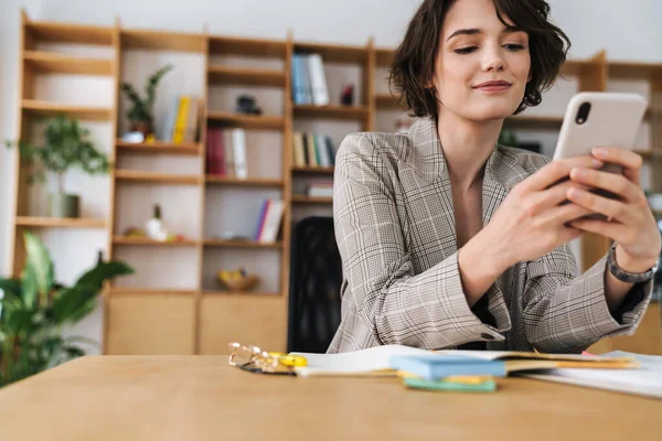 Gyönyörű Mosolygós Fiatal Üzletasszony Irodában Íróasztal Mobiltelefon — Stock Fotó