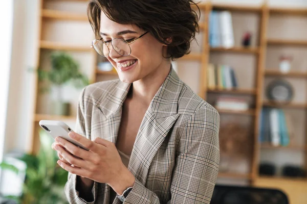 Hermosa Joven Mujer Negocios Sonriente Pie Oficina Utilizando Teléfono Móvil —  Fotos de Stock