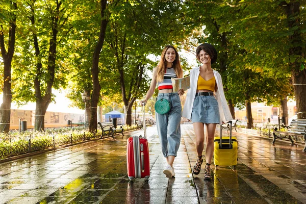 Foto Duas Mulheres Bonitas Felizes Sorrindo Segurando Mapa Enquanto Caminhava — Fotografia de Stock