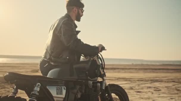 Jovem Feliz Brutal Rola Uma Motocicleta Enquanto Caminha Praia — Vídeo de Stock