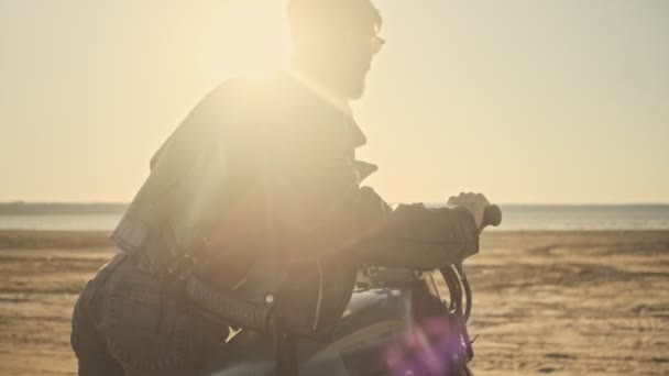 Brutální Sebevědomý Mladý Muž Válí Motocykl Při Chůzi Pláži — Stock video
