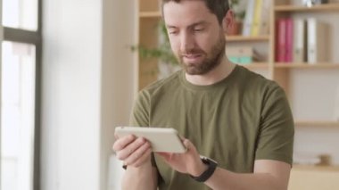 Yakışıklı, pozitif bir adam ofiste akıllı telefonunu kullanıyor.