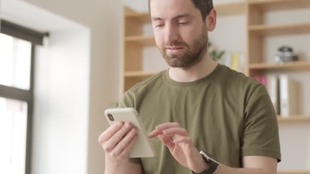 Snygg Positiv Man Använder Sin Smartphone Stående Kontoret — Stockvideo