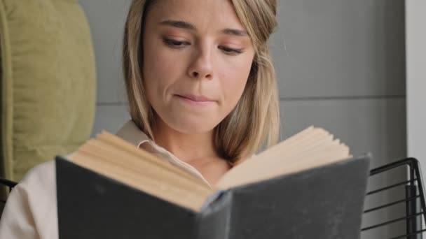 Χαμογελώντας Ελκυστική Ξανθιά Γυναίκα Ανάγνωση Βιβλίο Ενώ Κάθεται Στην Καρέκλα — Αρχείο Βίντεο