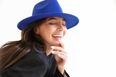 Gülen iyimser, mavi şapkalı, beyaz duvar arkasında izole edilmiş mutlu bir kadının görüntüsü..