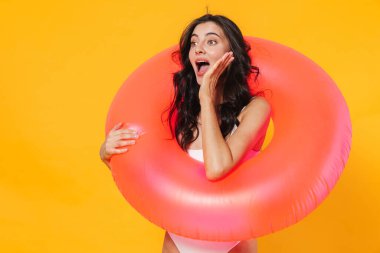 Sarı duvarda izole edilmiş lastik halkalı heyecanlı genç bir kadın görüntüsü.