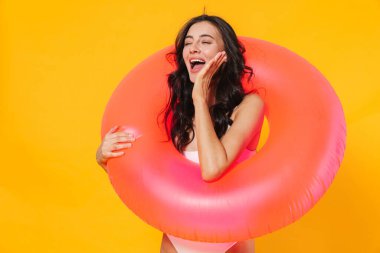 Sarı duvarda izole edilmiş lastik halkalı heyecanlı genç bir kadın görüntüsü.