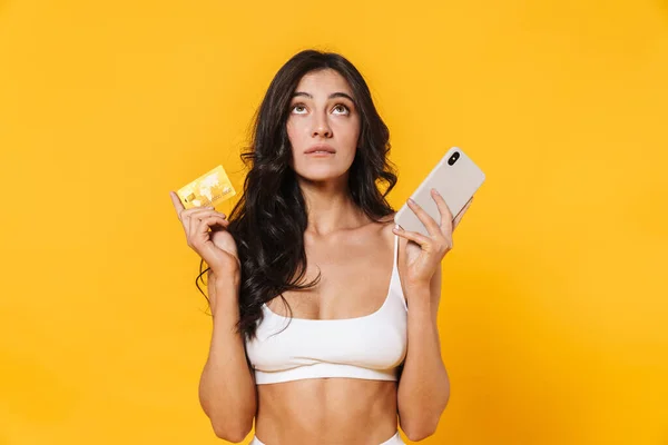 Image Thinking Woman Swimsuit Holding Credit Card Cellphone Isolated Yellow — Stock Photo, Image