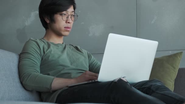 Ein Hübscher Junger Asiatischer Mann Mit Brille Benutzt Seinen Laptop — Stockvideo