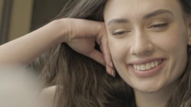 İçerde otururken laptopunu kullanan neşeli, esmer kadının yakın görüntüsü.