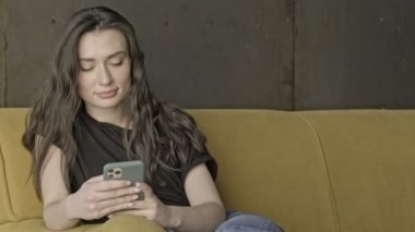 Kapalı koltukta otururken akıllı telefon kullanan güzel esmer kadın.