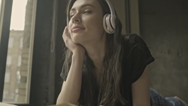 Χαμογελώντας Μυστήριο Μελαχρινή Γυναίκα Ακουστικά Κοιτάζοντας Γύρω Στη Συνέχεια Διαβάζοντας — Αρχείο Βίντεο