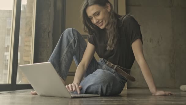 快乐漂亮的黑发女人坐在室内的地板上用手提电脑 — 图库视频影像