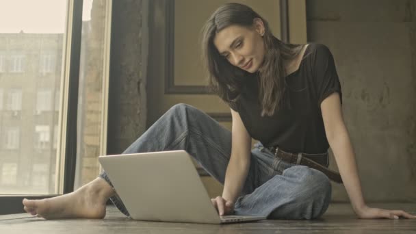 Красивая Брюнетка Сидящая Полу Помещении Пользуется Ноутбуком — стоковое видео