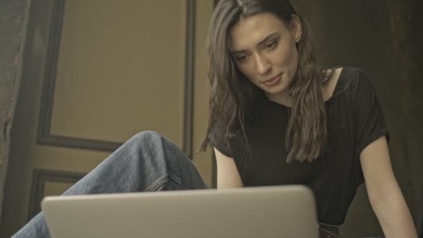 坐在室内地板上 用手提电脑安抚漂亮的黑发女人 — 图库视频影像
