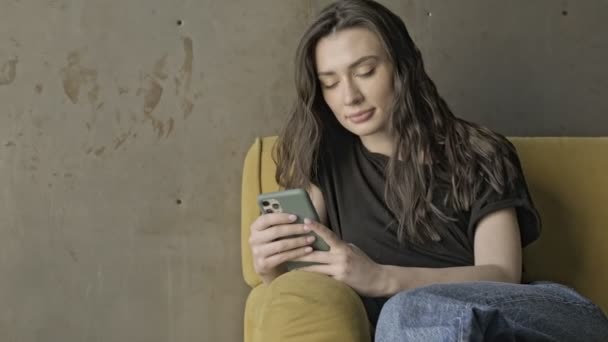 Carefree Hezká Brunetka Žena Pomocí Smartphone Zatímco Sedí Pohovce Uvnitř — Stock video