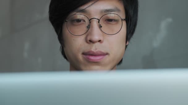 Крупный План Привлекательного Спокойного Молодого Азиата Очках Смотрит Свой Ноутбук — стоковое видео