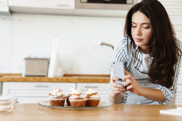 Kafkas Yoğunlaştırılmış Önlük Giymiş Bir Kadının Modern Mutfakta Cep Telefonuyla — Stok fotoğraf