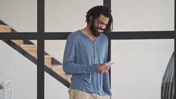 Usmívající Mladý Africký Američan Používá Svůj Smartphone Obývacím Pokoji Doma — Stock video
