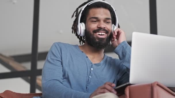 Jovem Afro Americano Feliz Usando Fones Ouvido Está Usando Seu — Vídeo de Stock