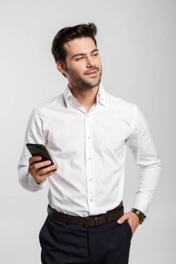 Kol saatinde mutlu bir iş adamının görüntüsü cep telefonuyla yazı yazması ve beyaz arka planda izole bir şekilde gülümsemesi.