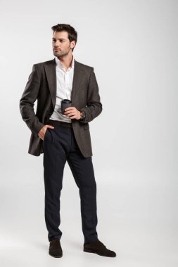 Beyaz arka planda izole edilmiş kahve içen ceketli başarılı genç iş adamının görüntüsü