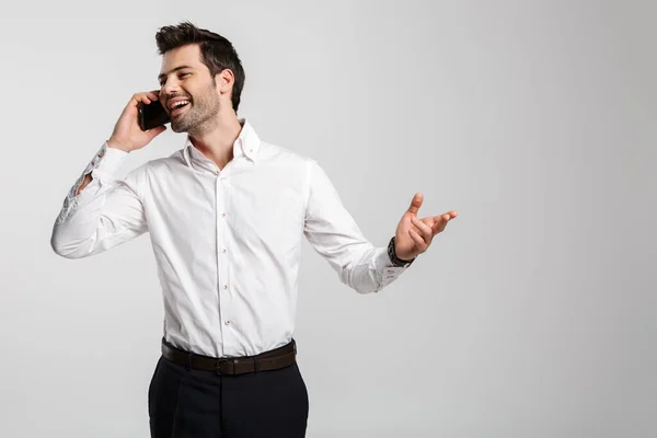 照片中快乐而成功的商人在手表上一边用手机交谈 一边在白色背景下面带微笑 — 图库照片