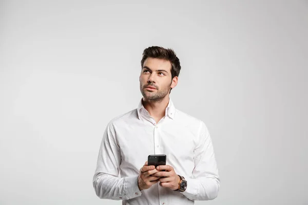 照片中年轻的思考商人在手表上用手机打字 在白色背景下向上看 — 图库照片
