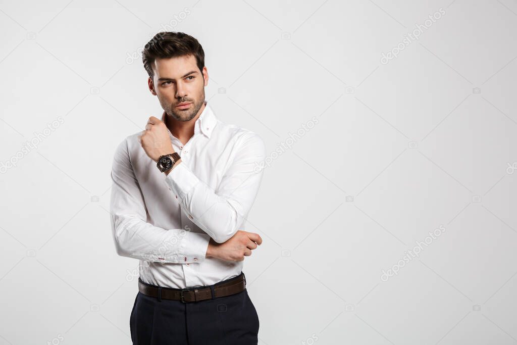 Image of young caucasian businessman in wristwatch posing and looking aside isolated over white background