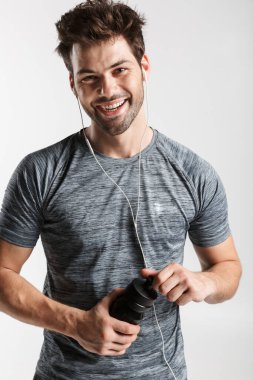 Kulaklık takan ve elinde su şişesi tutan genç bir adamın görüntüsü.