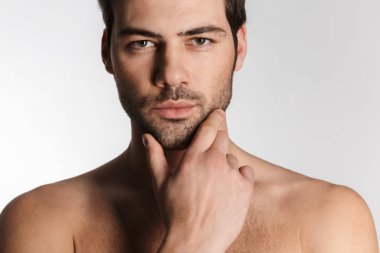 Beyaz arka planda izole edilmiş, poz veren ve kameraya bakan kendinden emin yarı çıplak bir adamın fotoğrafı.