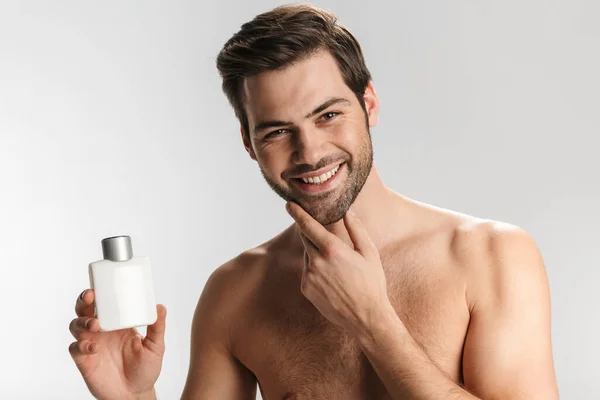 Photo Joyful Half Naked Man Smiling Showing Moisture Lotion Isolated — Stock Photo, Image
