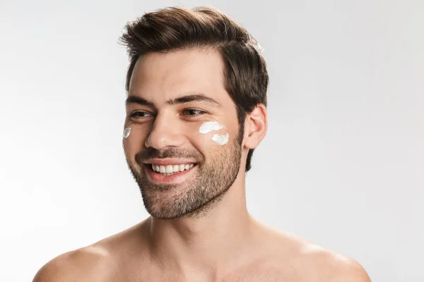 Foto Alegre Hombre Semidesnudo Con Crema Facial Sonriendo Mirando Lado —  Fotos de Stock