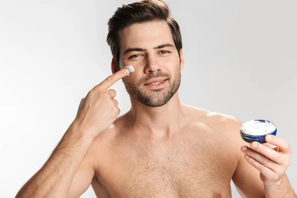 Photo Pleased Half Naked Man Looking Camera Applying Facial Cream — Stock Photo, Image