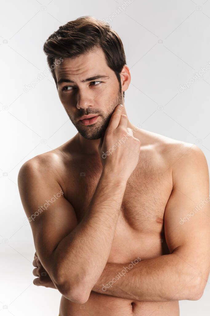 Photo of athletic half-naked man posing and looking aside isolated over white background