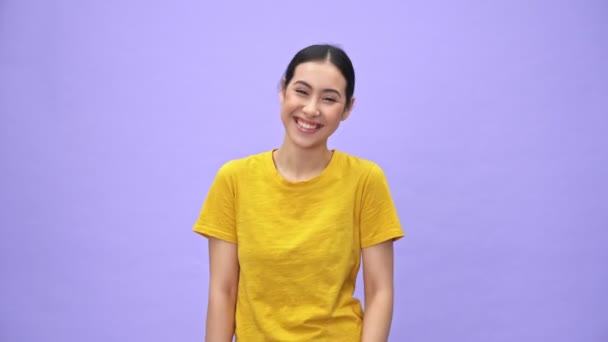 穿着黄色T恤的快乐漂亮的女运动员在镜头前竖起大拇指 在紫罗兰的背景下尽情欢乐 — 图库视频影像