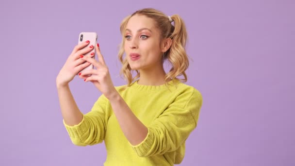 Uma Linda Loira Tira Uma Selfie Telefone Grimeiras Estúdio Isolado — Vídeo de Stock