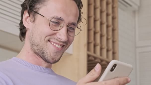 Close Vista Homem Bonito Sorridente Óculos Usando Smartphone Casa — Vídeo de Stock