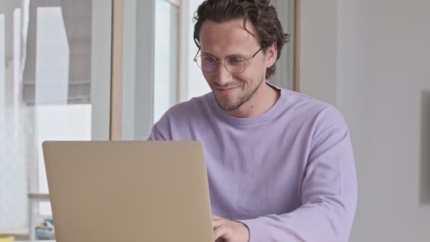 Hombre Guapo Sonriente Gafas Usando Computadora Portátil Junto Mesa Casa — Vídeo de stock